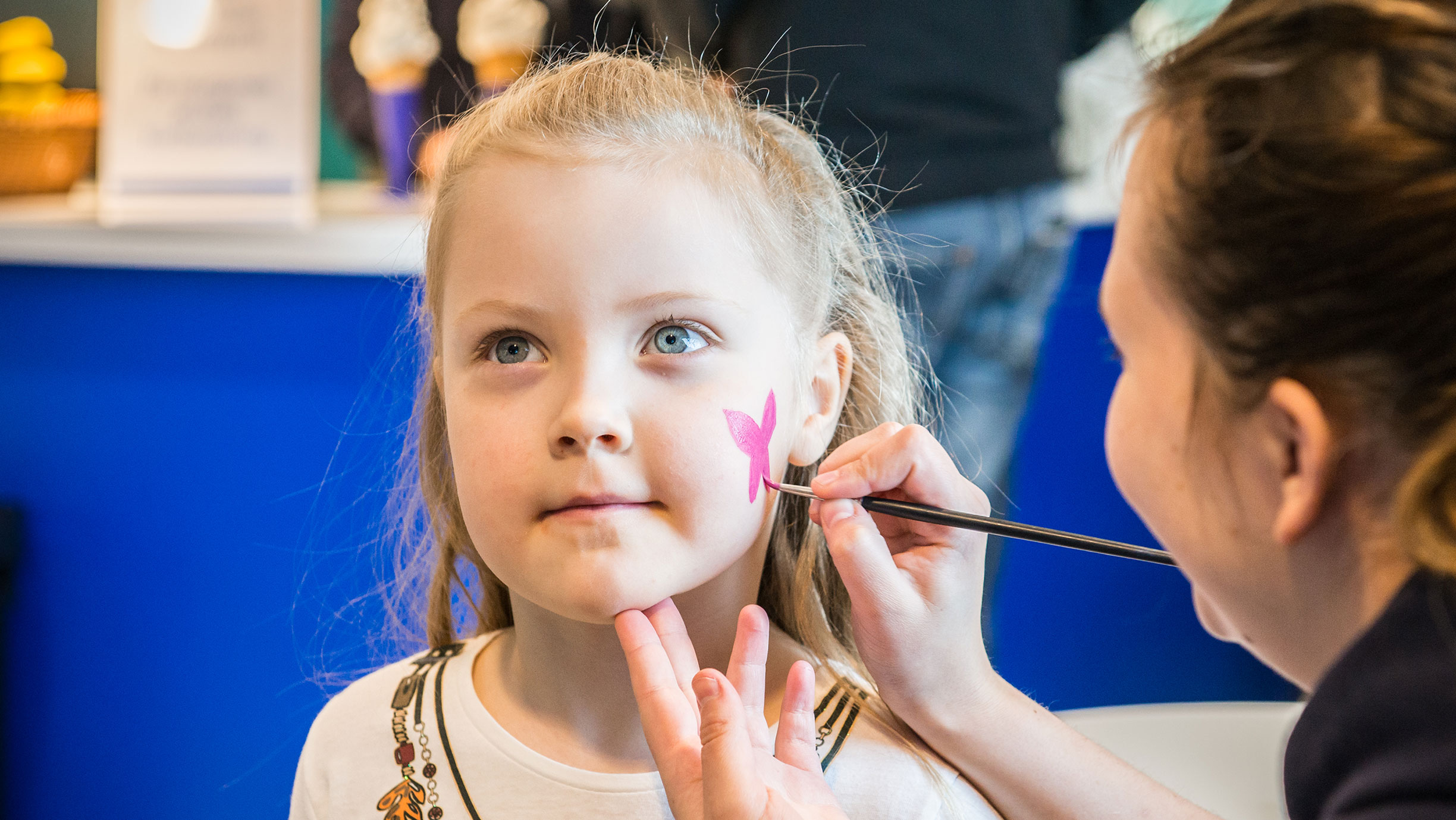 Närbild på ett barn med ansiktsmålning med morrhår och nos, som en tiger eller katt.