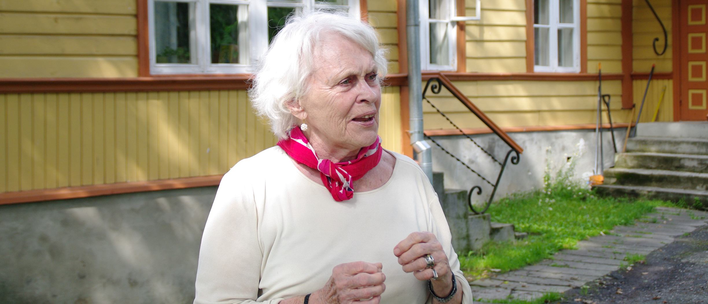 Ilon Wikland utanför ett gult hus