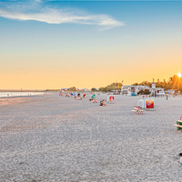 Människor sitter på Pärnu beach i solnedgången