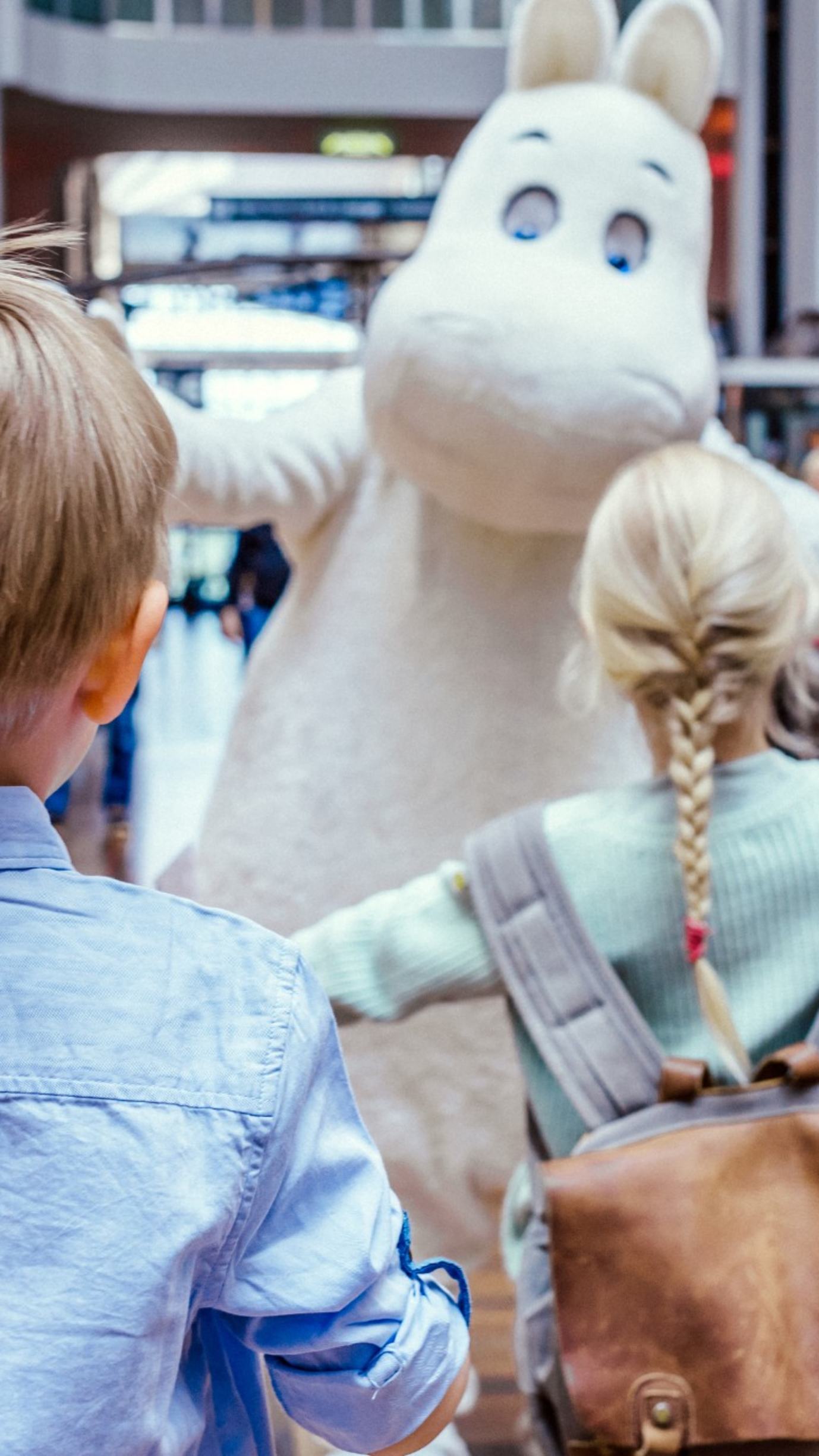 En flicka på väg att krama Mumin.