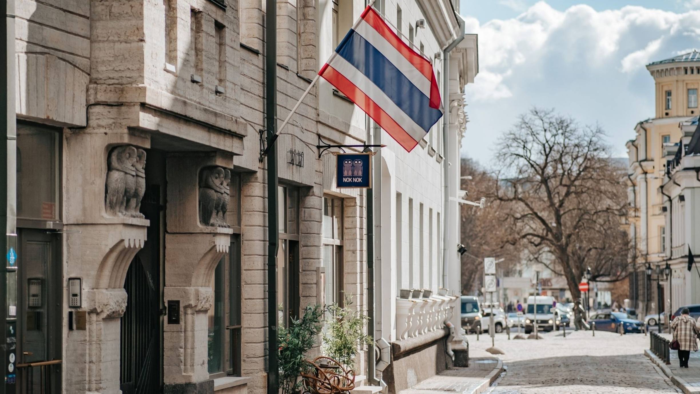 Ulkonäkymä NOK NOKin ravintolasta, jossa näkyy vanhankaupungin katuja, arkkitehtuuria ja sisäänkäynnin kohdalla liehuva Thaimaan lippu.