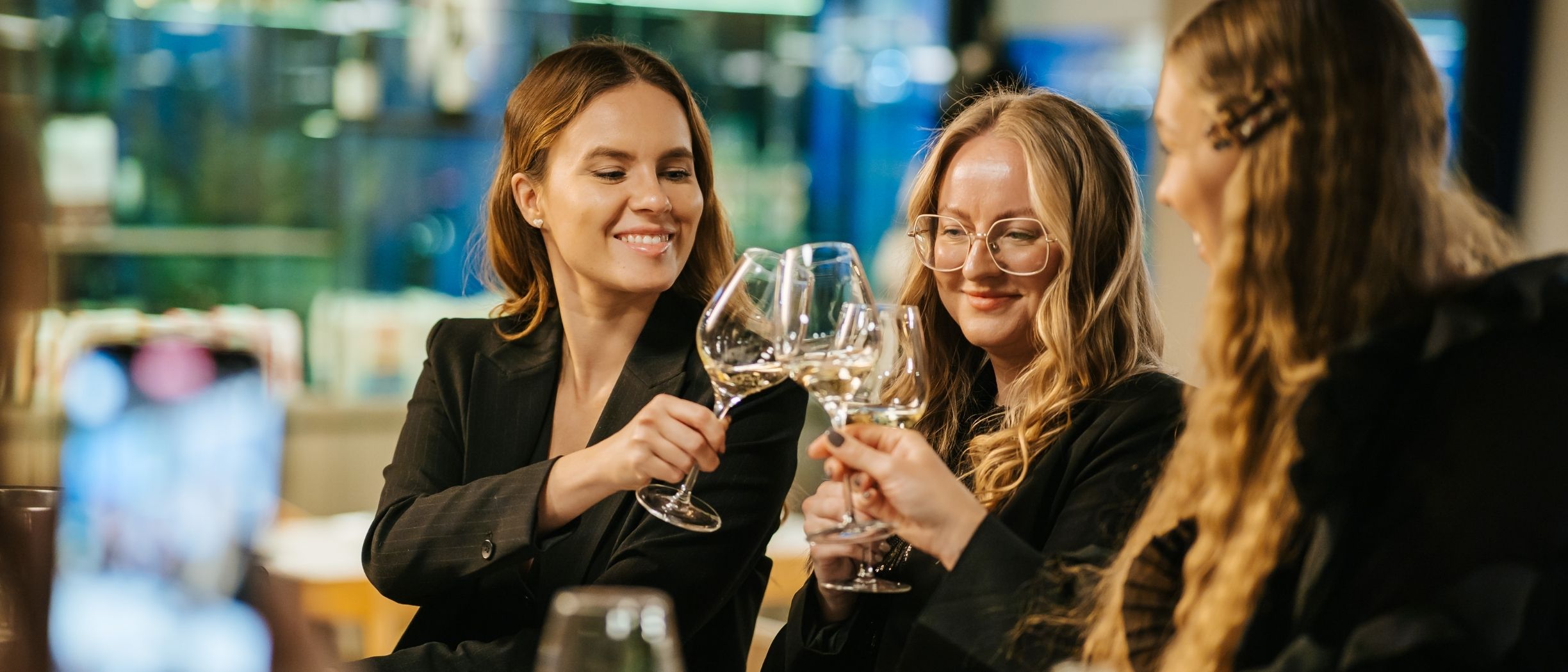 Two women are clinking sparkling wine glasses during the workshop.
