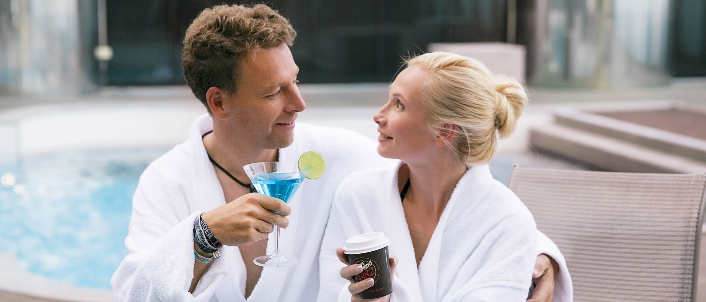 A man and a woman in the spa in bathrobes and cocktails in hand