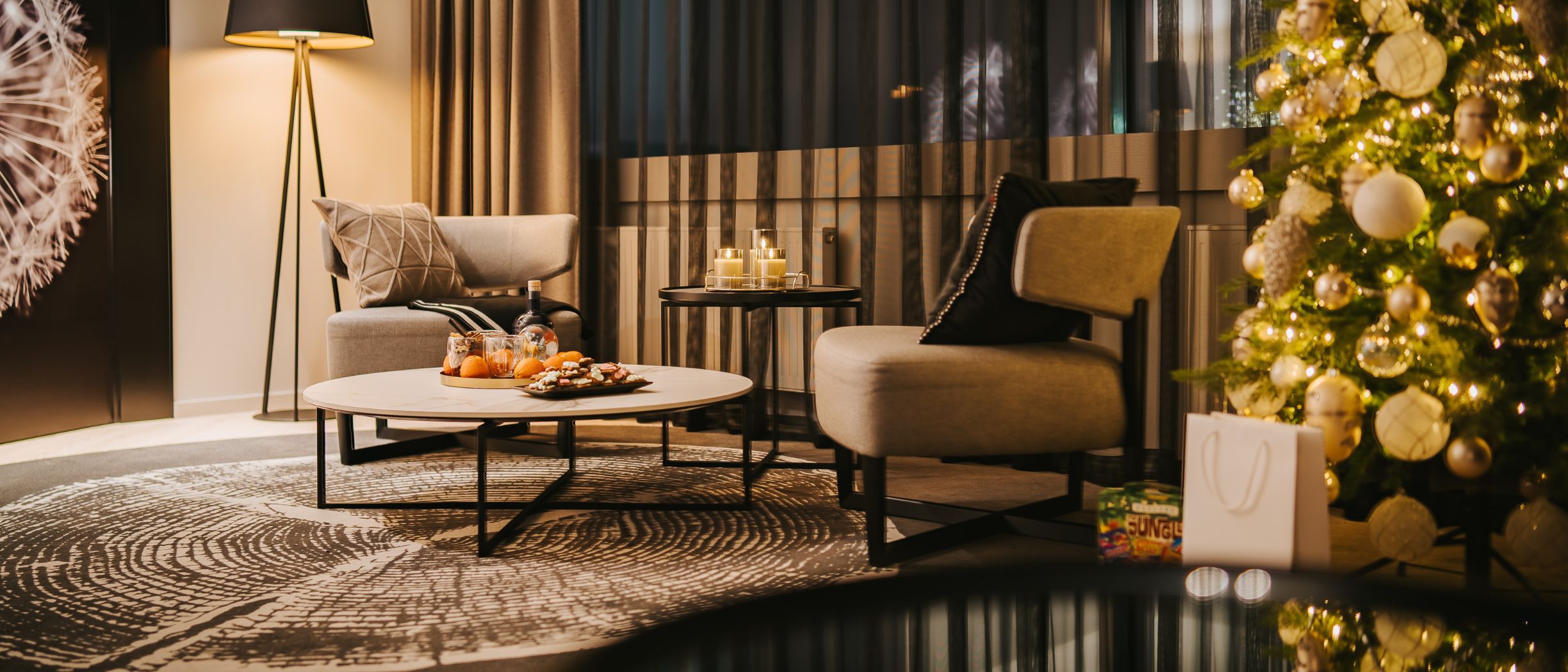 A Christmas suite, featuring a decorated living room and a Christmas tree. The table is set with mulled wine, mandarins, and gingerbread cookies.