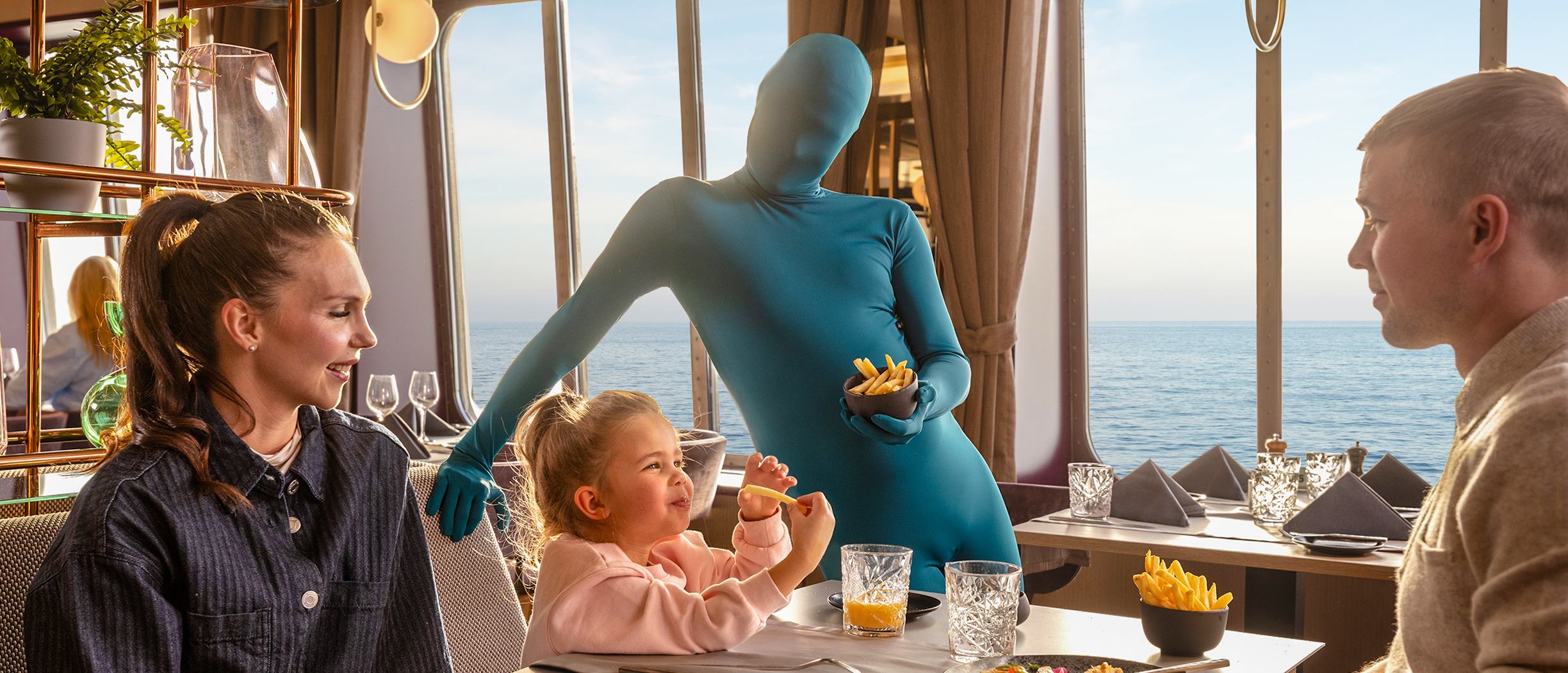 Perhe syö Tallink Shuttle -laivalla ja sininen Shuttle Effect -hahmo huolehtii, että lapsella on ranskalaisia perunoita