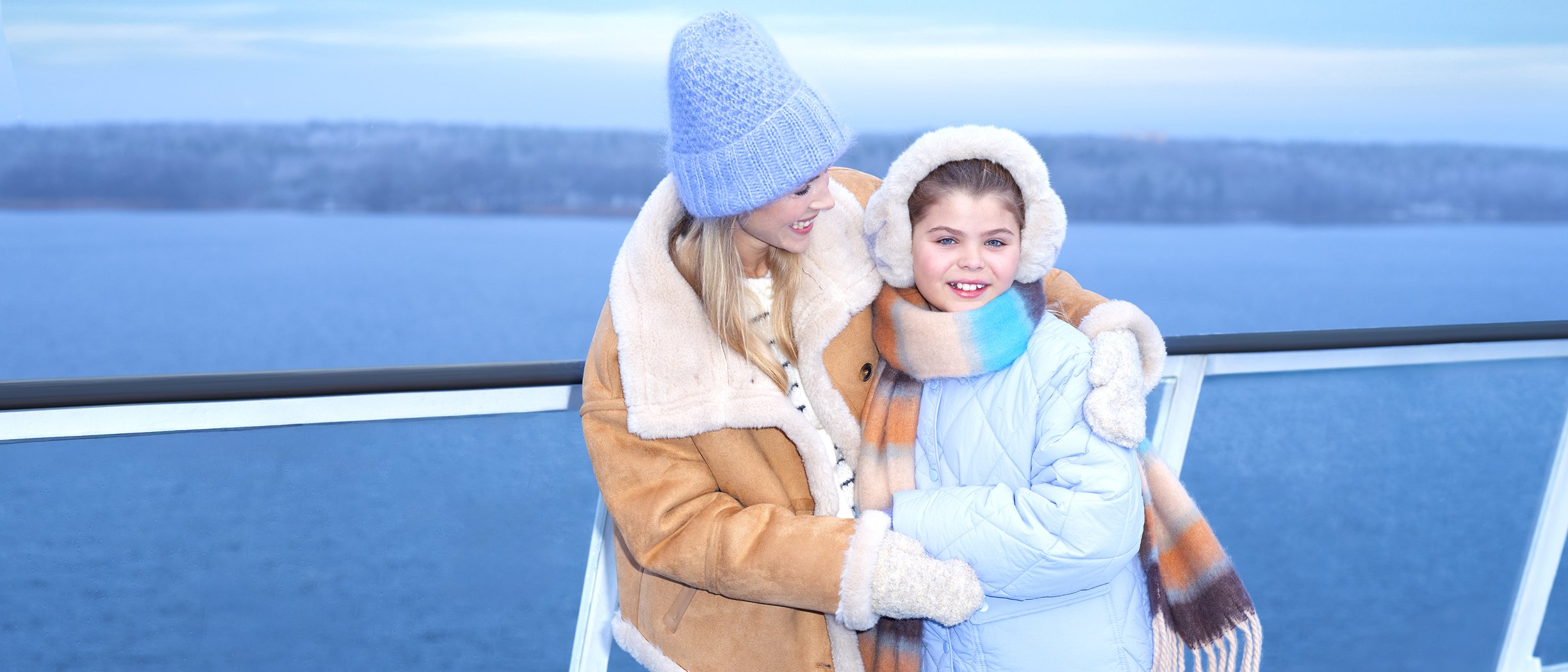 Mother and daughter posing for the camera on ship's sundeck in wintertime