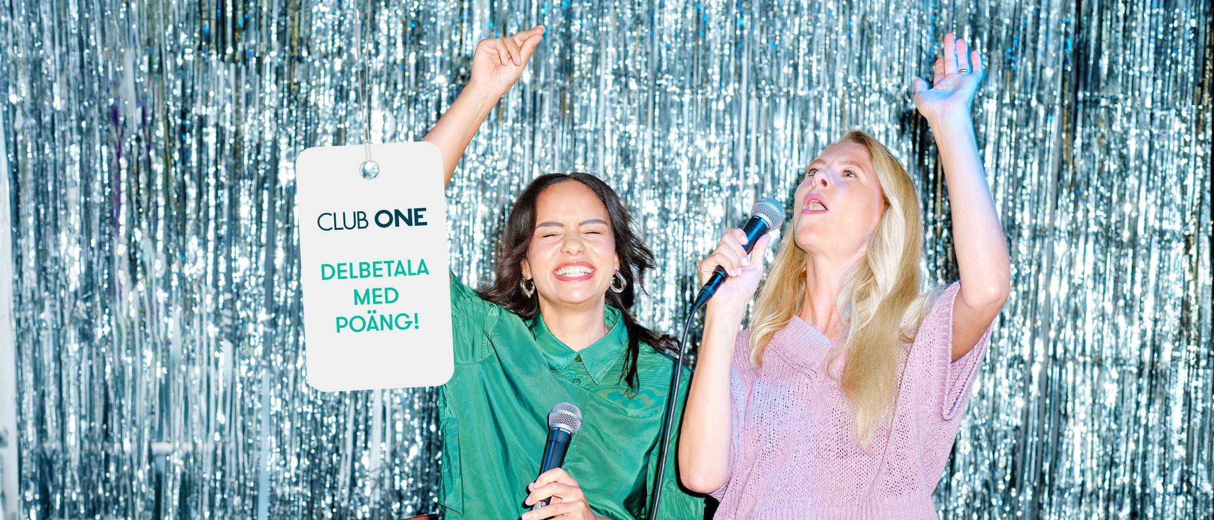 Två glada tjejer sjunger karaoke framför ett silvrigt glitterdraperi