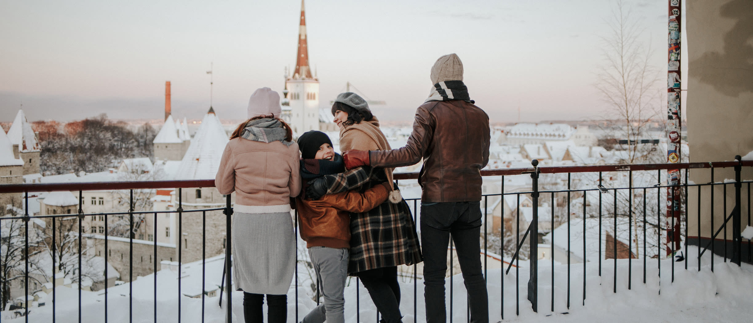 En familj står på en utsiktsplattform i Tallinn och tittar ut över ett snötäckt Gamla stan