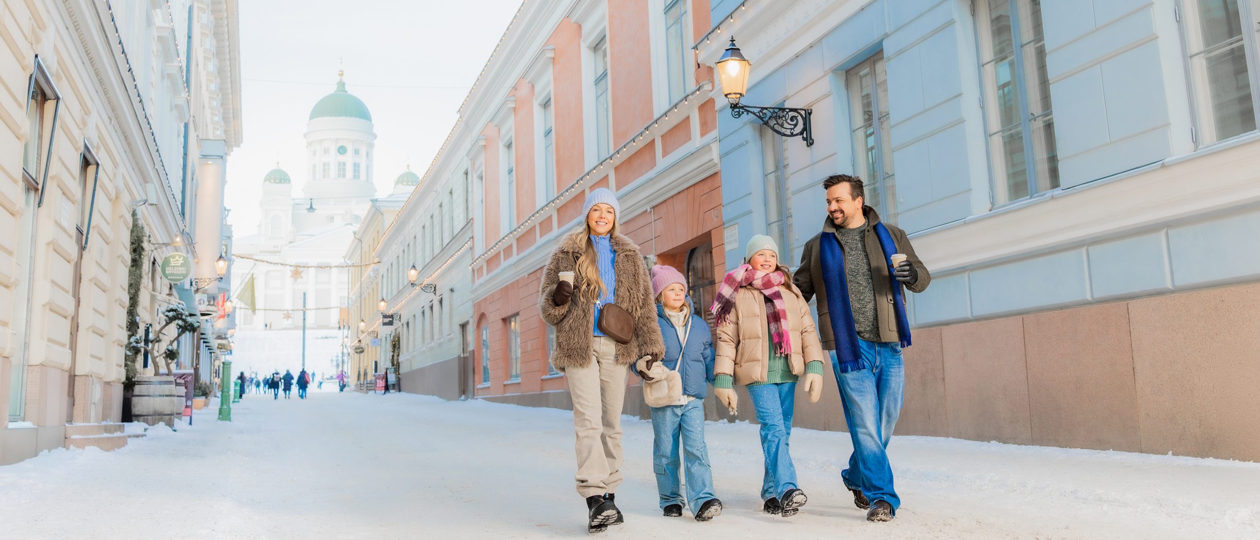 En familj går på en gata i Helsingfors, Finland, med Domkyrkan på Senatstorget i bakgrunden