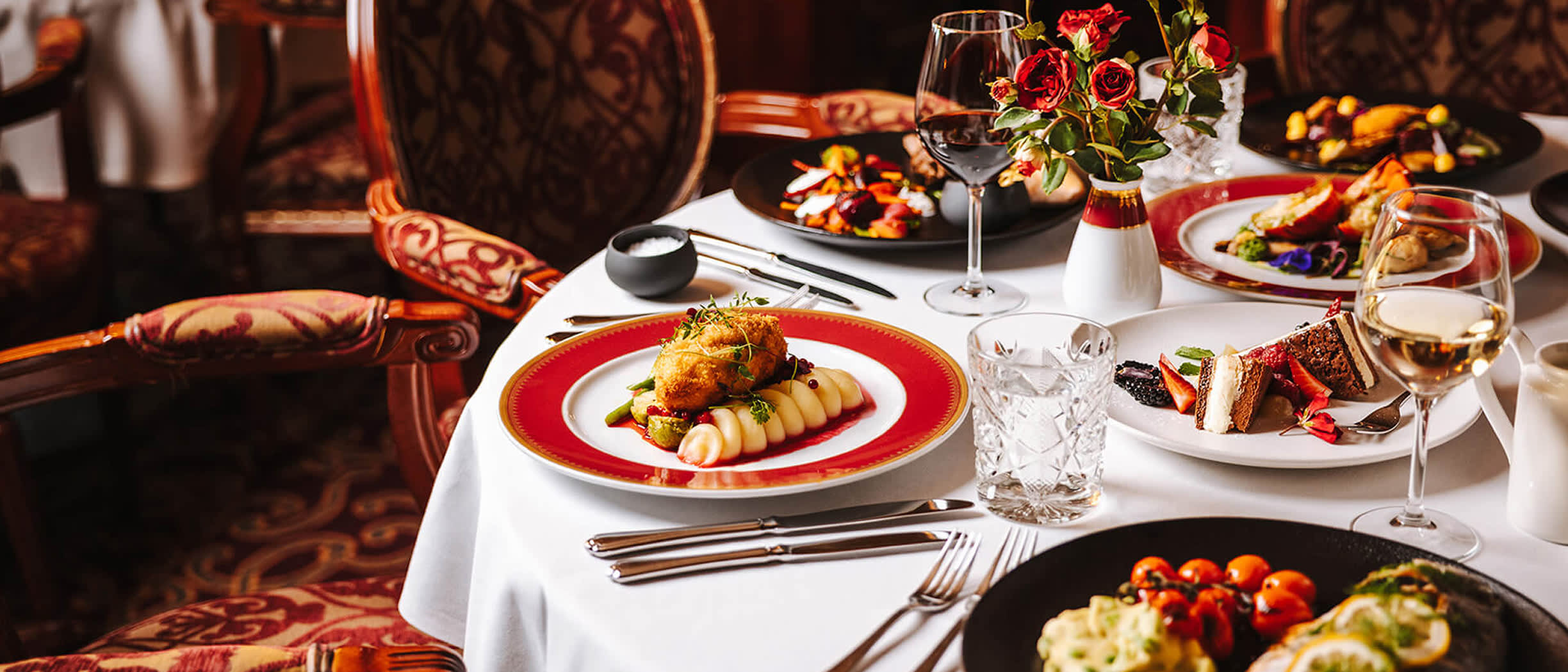 Aleksandra restaurant meal setup on Baltic Queen with Slavic dishes, wine, and dessert on a white tablecloth