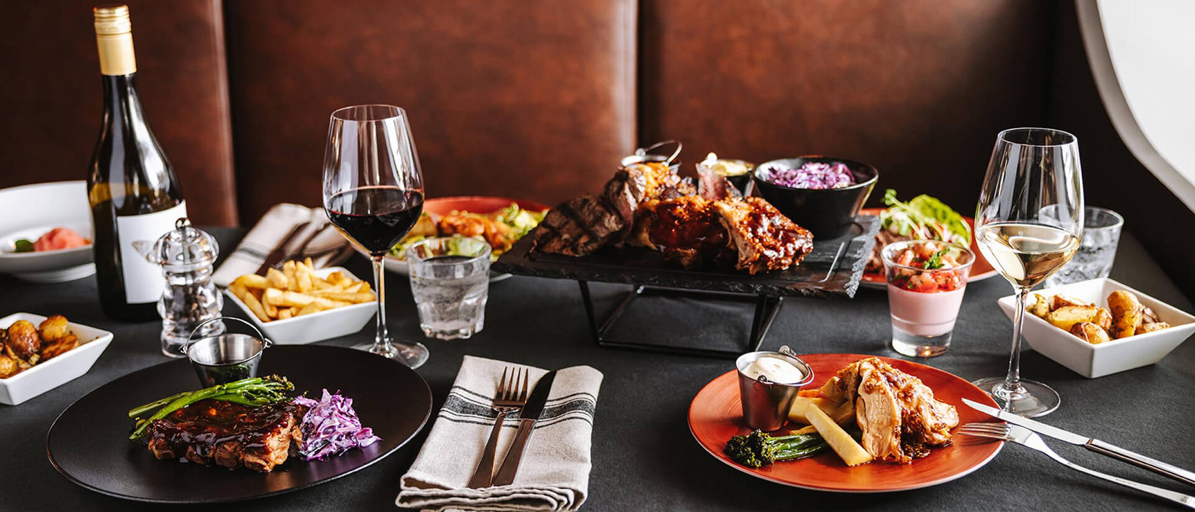 Grill House dinner setup on Baltic Queen with grilled meats, side dishes, and wine