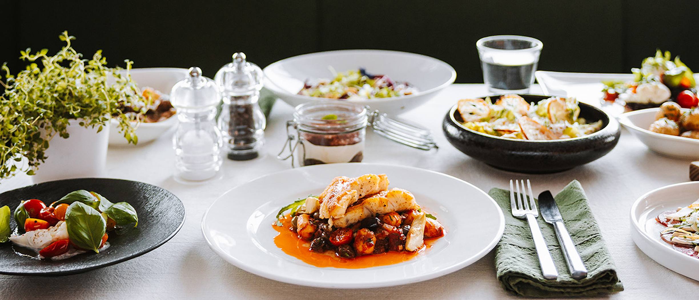 A beautifully set table at Tavolata Italian restaurant on a Tallink ship, featuring Mediterranean dishes, salads, and desserts served in a relaxed atmosphere.