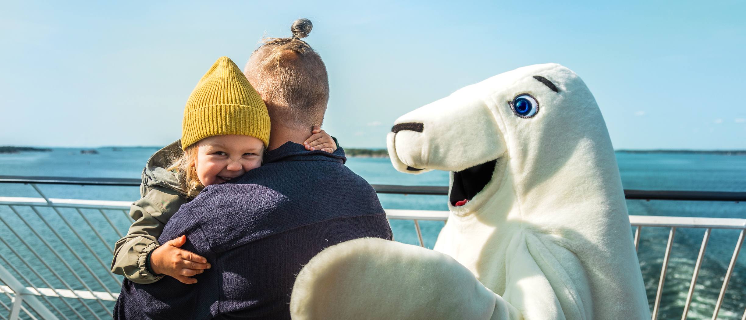 Isä ja lapsi sekä Harri Hylje laivan kannella saaristomaisemissa