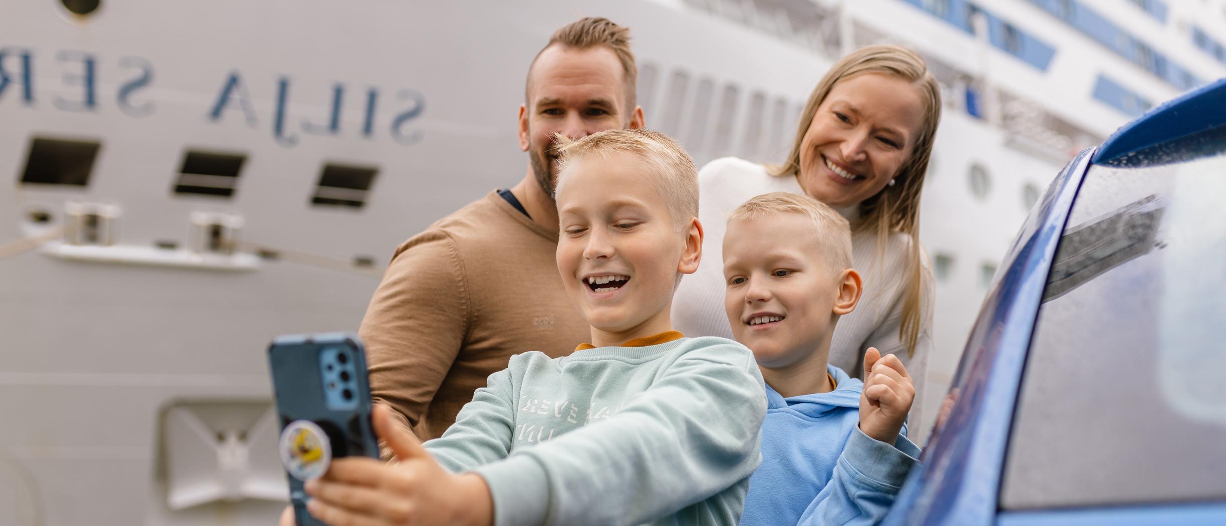 Eine Familie posiert vor einem Tallink Silja Line Schiff für ein Selfie.