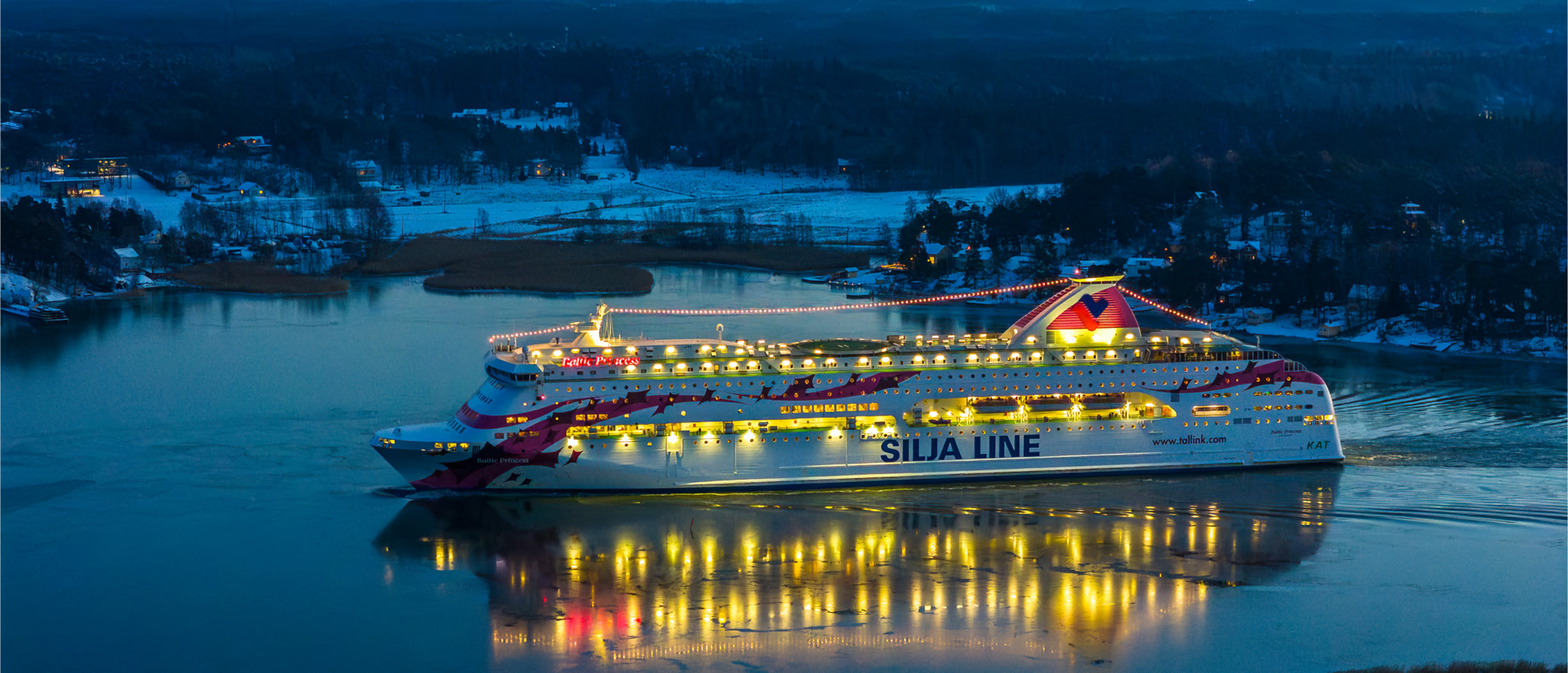 Baltic Princess sailing, glittering lights and snowy shores in the background