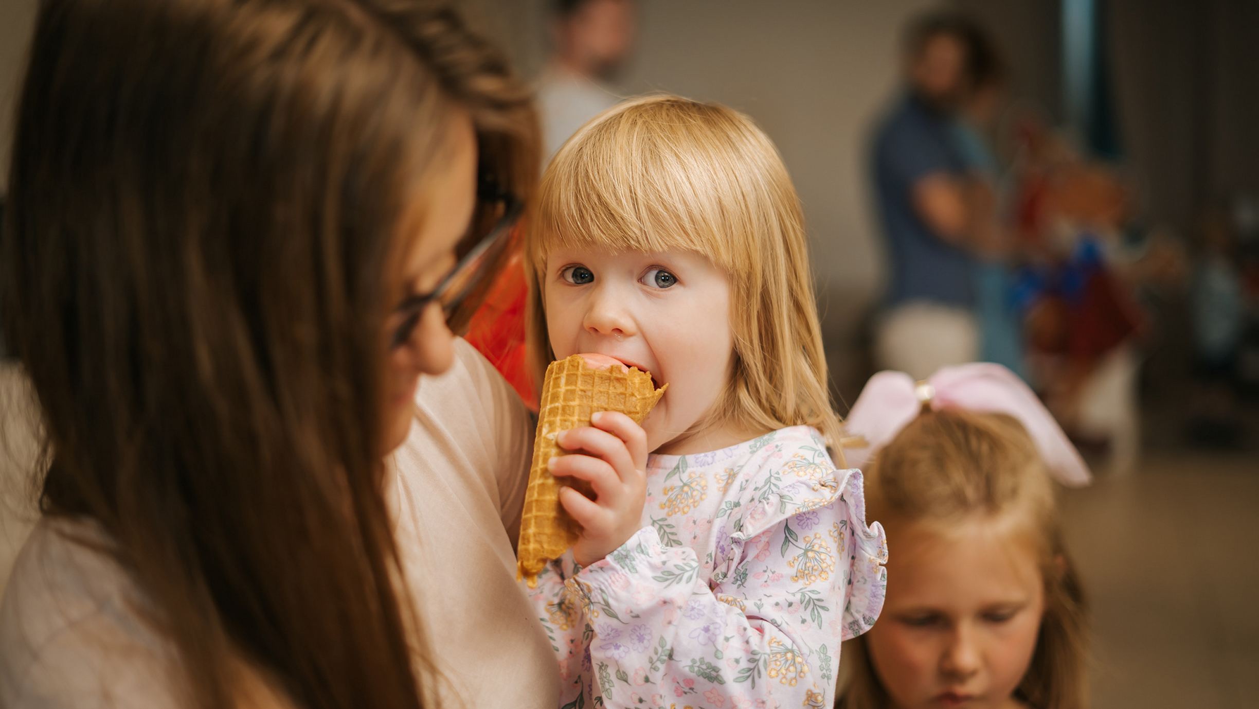 Girl eating ice cream in mother's arms