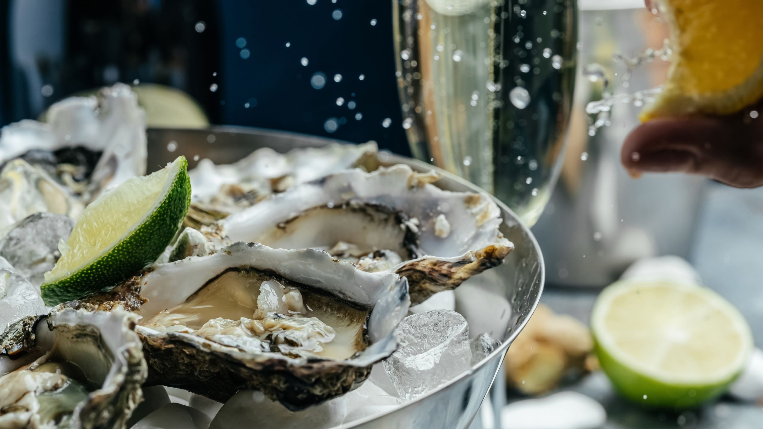 A closeup of oysters and champagne classes on a lavishly set up table.