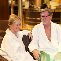 Ett äldre par sitter i morgonrockar på relaxavdelningen ombord Baltic Queen, färjan som åker Stockholm-Tallinn