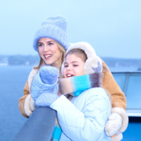 En mamma och dotter står ute på däck en vinterdag på kryssning