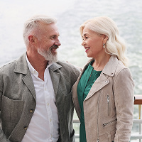 Vanhempi pariskunta katselee toisiaan laivan kannella merimaisemissa